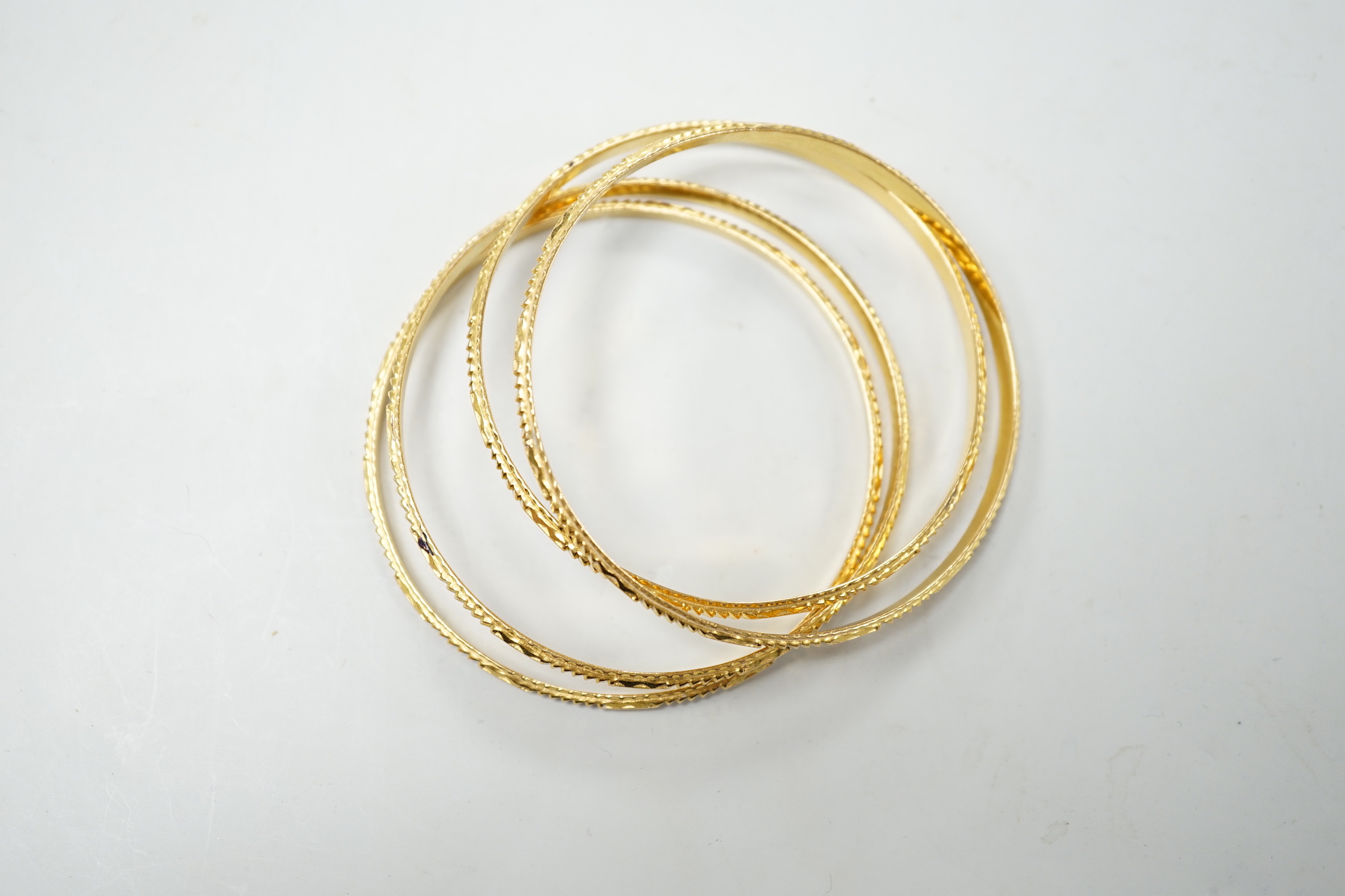 A set of four bright cut yellow metal bangles, 60 grams.